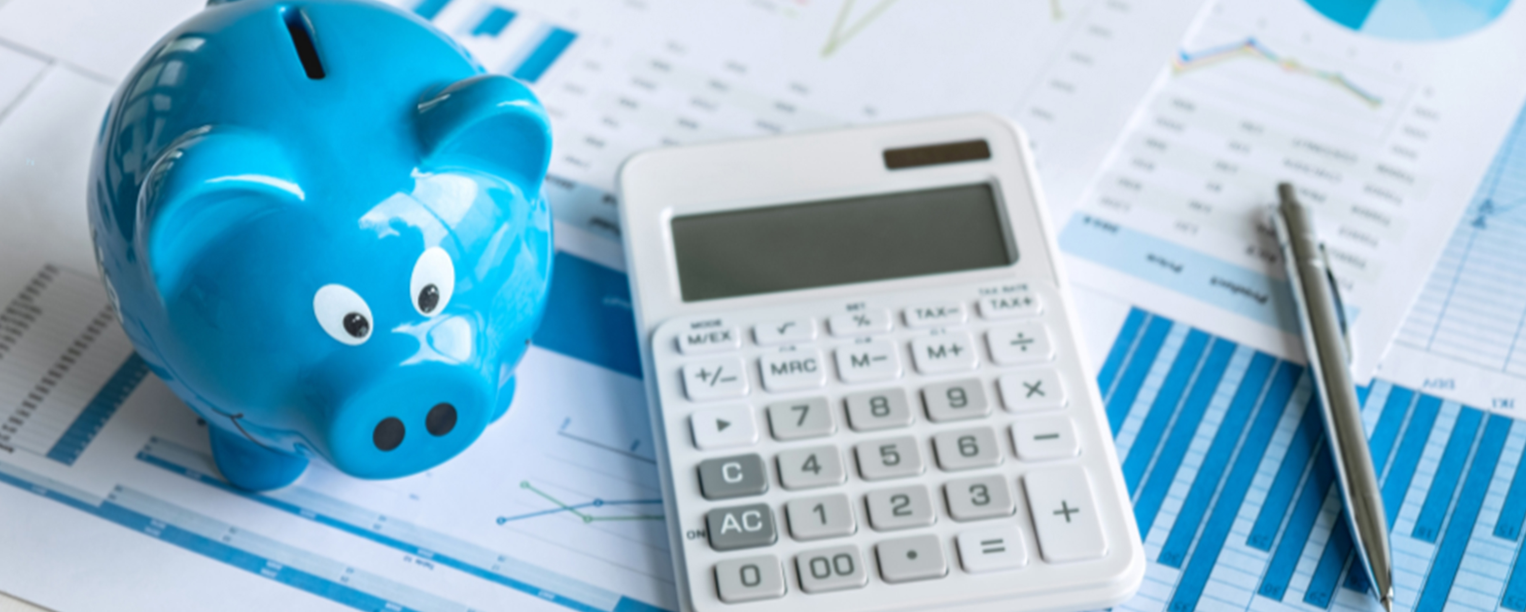 A calcuator and a blue piggy bank on top of tax papers