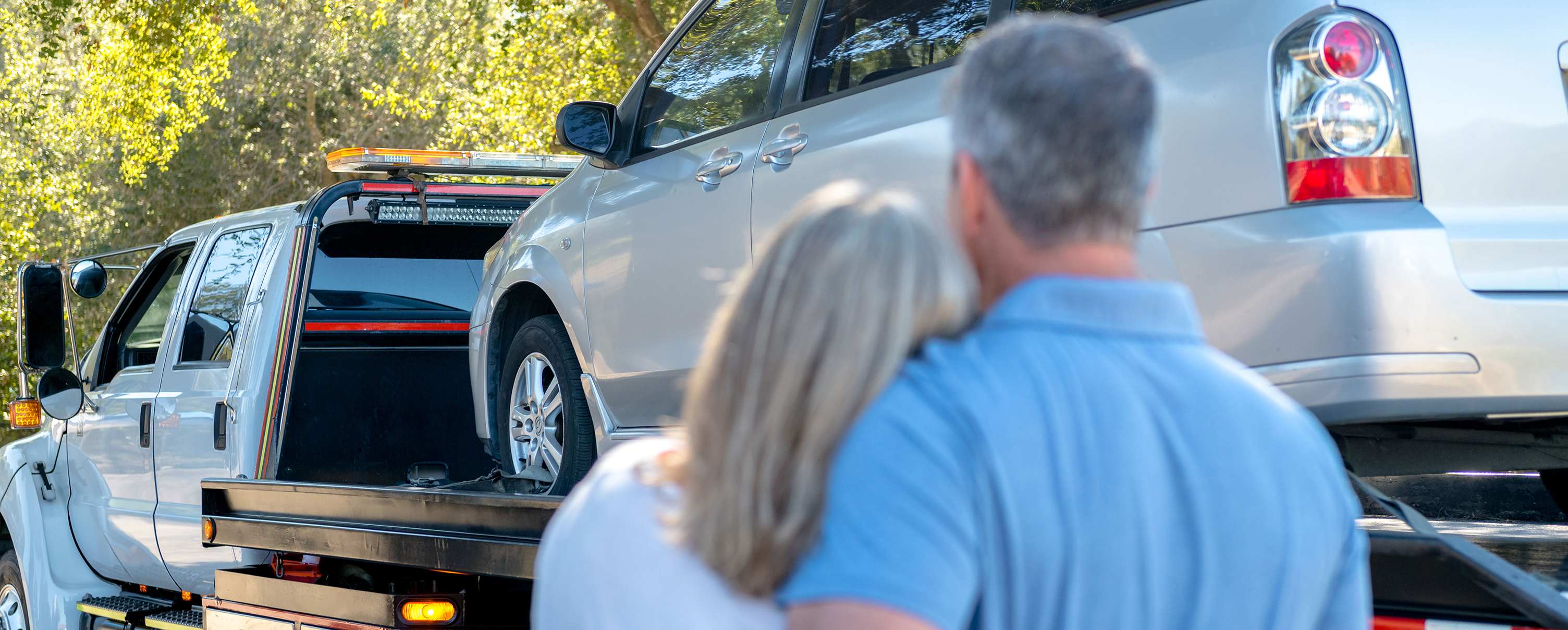 Couple holding each other while car getting towed